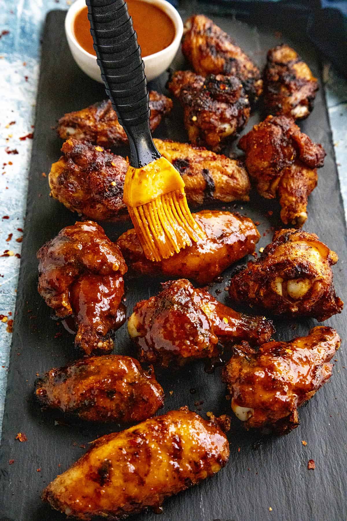 Brushing chicken wings with honey-sriracha sauce