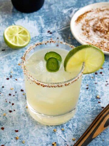 A spicy margarita in a glass with a salt and tajin coated rim