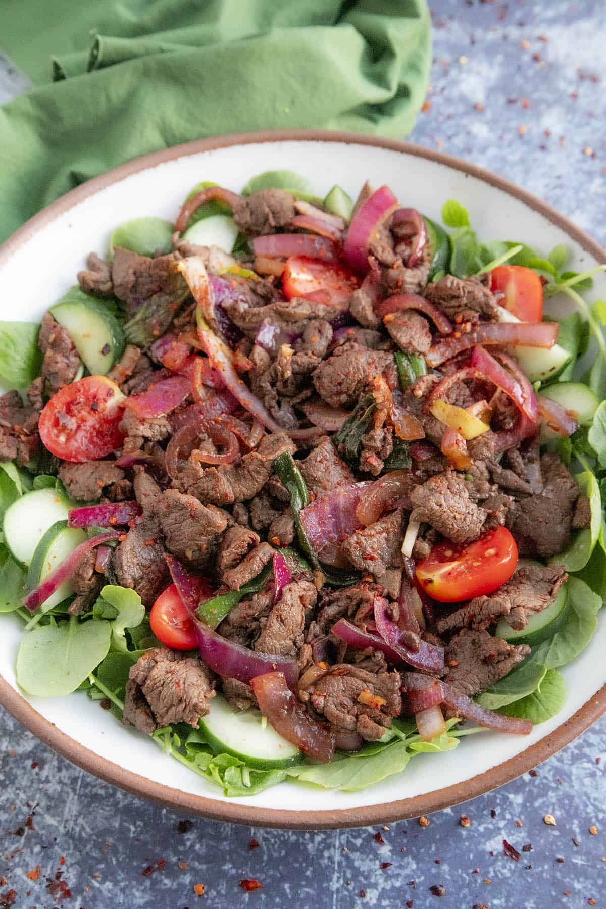 Vietnamese Shaking Beef (Bo Luc Lac) in a bowl over greens