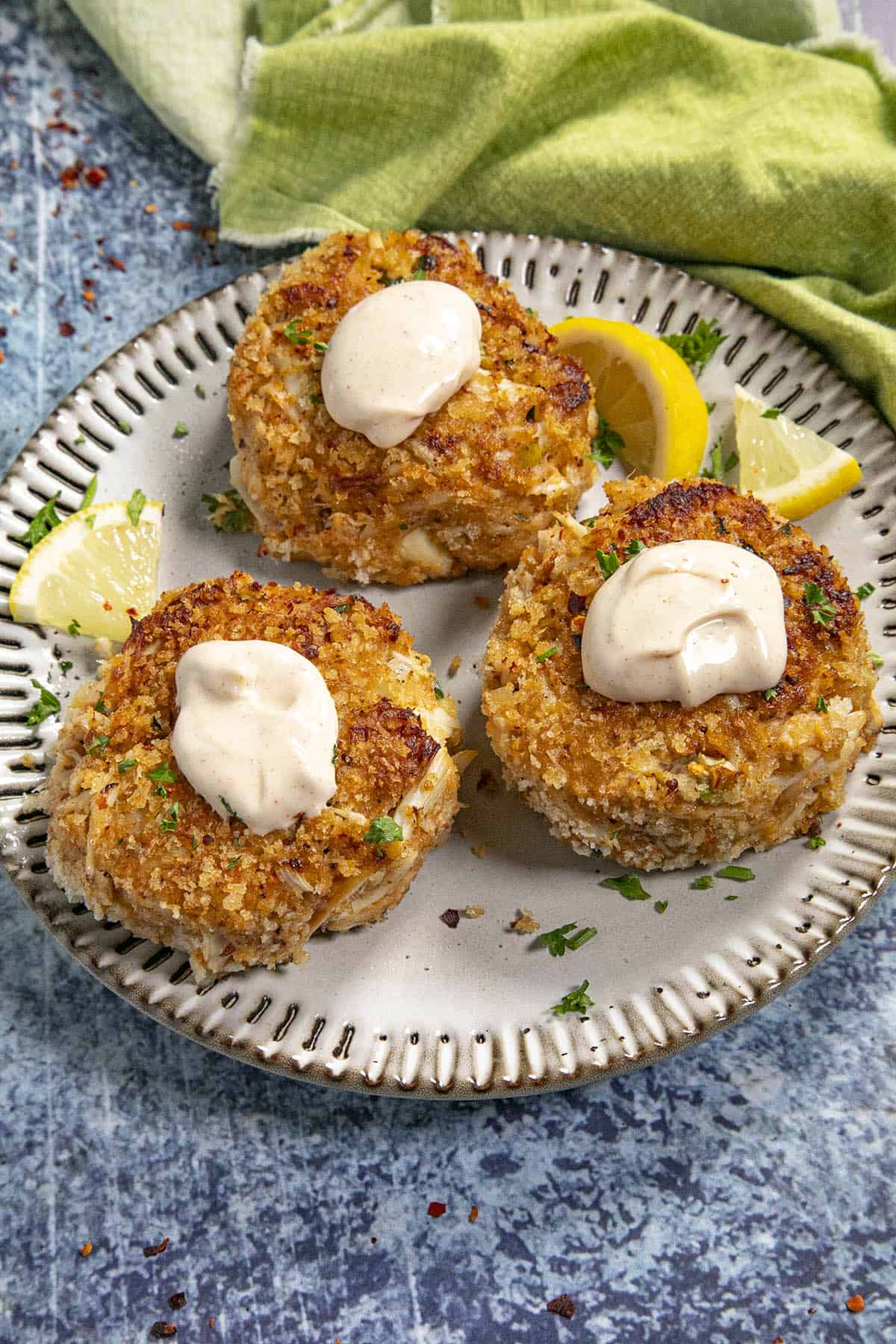 3 Crab cakes with creamy crab cake sauce on a plate for serving