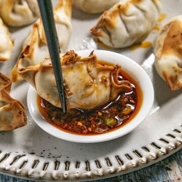 Dipping a piece of gyoza into a bowl of spicy gyoza sauce