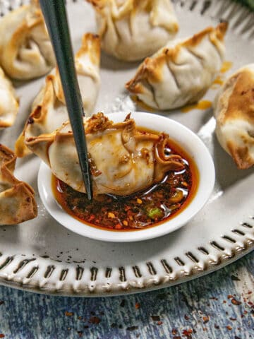 Dipping a piece of gyoza into a bowl of spicy gyoza sauce