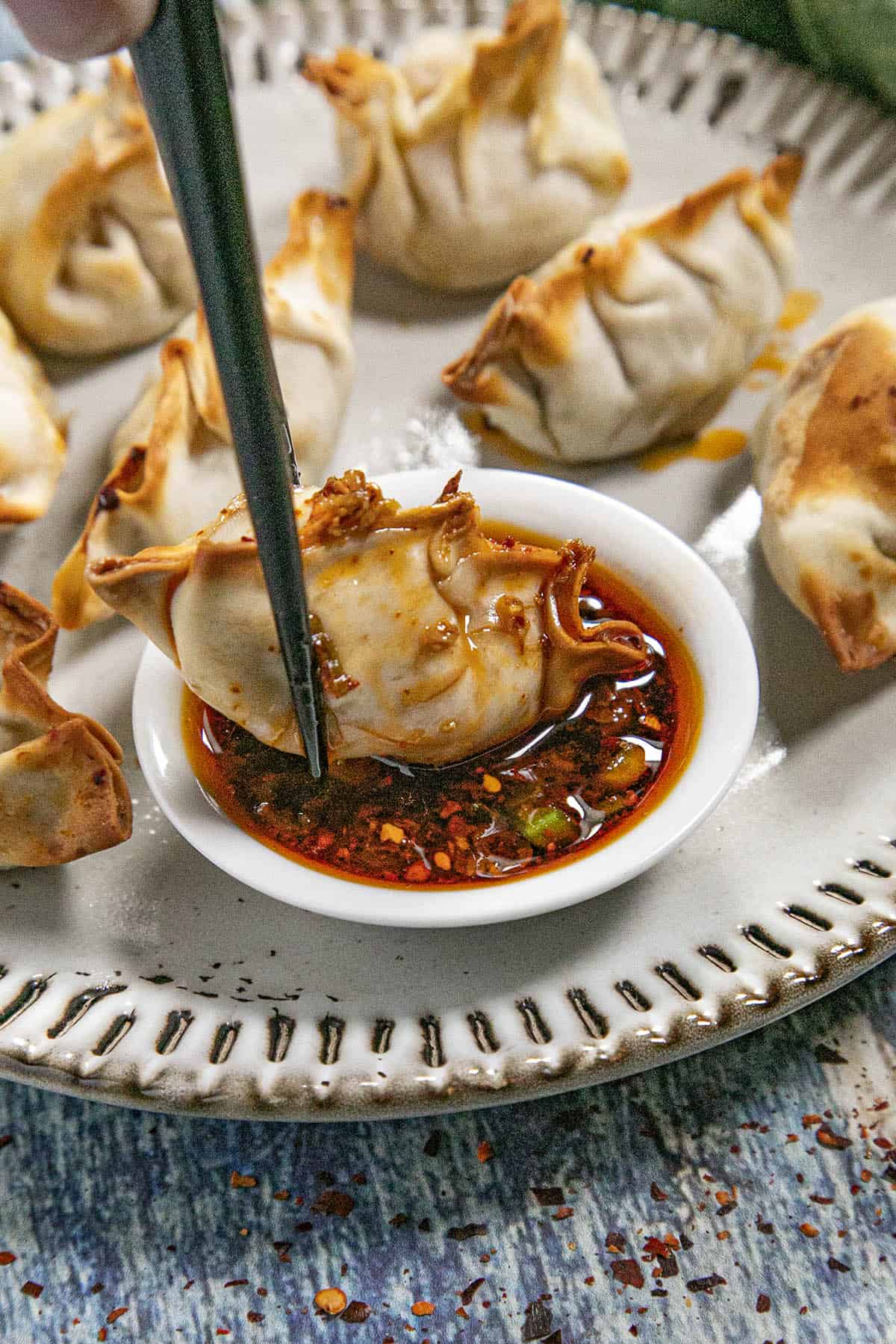 Dipping a piece of gyoza into a bowl of spicy gyoza sauce