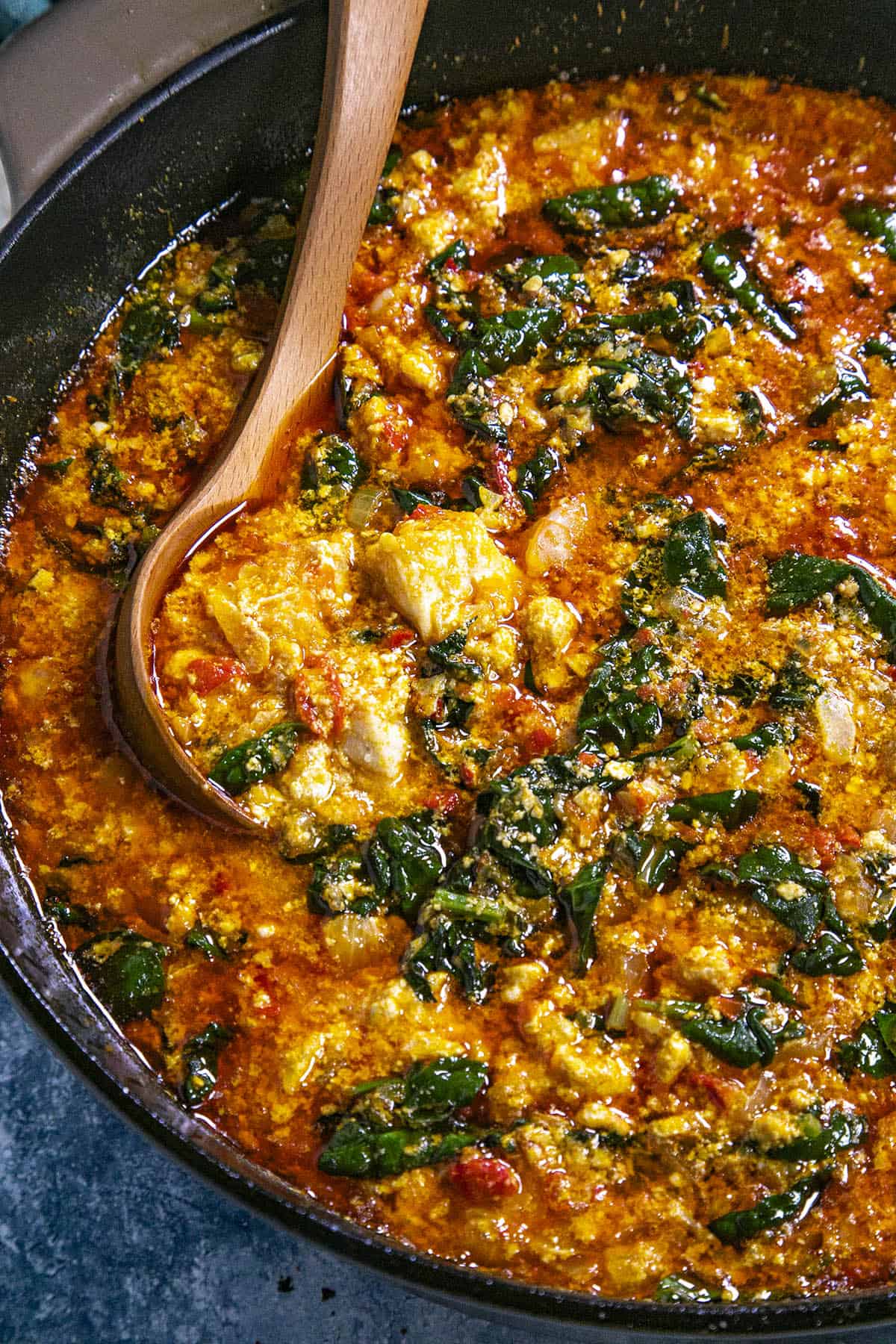 Swirling egusi soup in the pot with a spoon