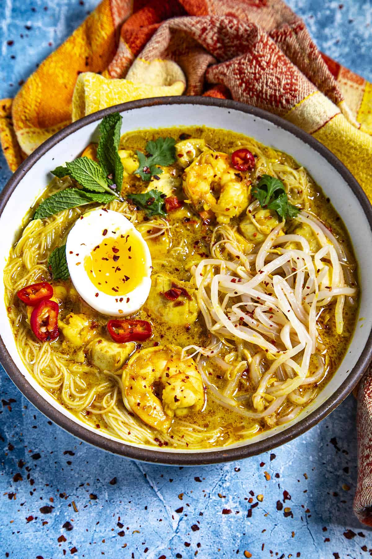 Serving a bowl of Homemade Coconut Curry Laksa with lots of garnish