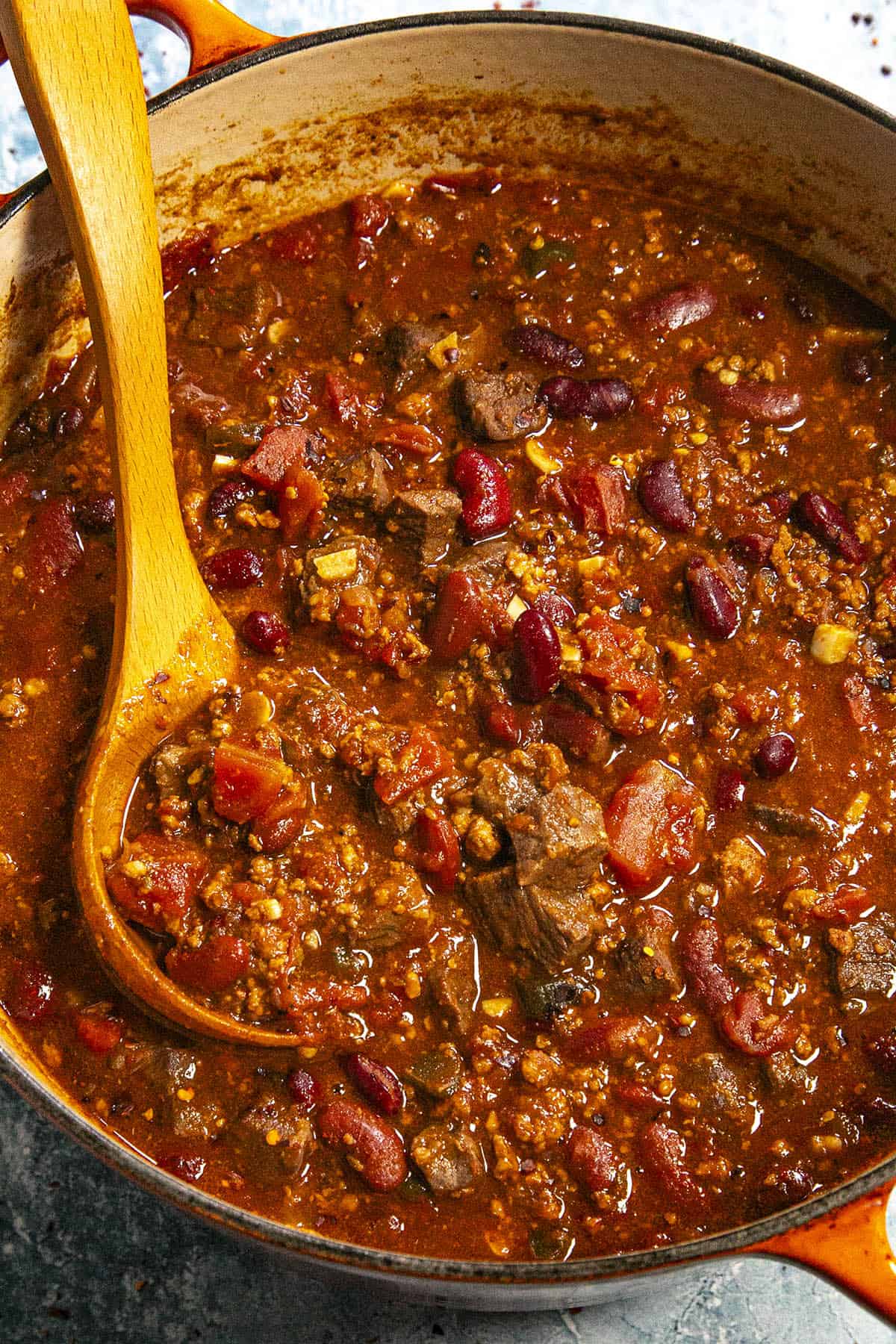 Scooping a spoonful of Short Rib and Chorizo Chili from the pot with a serving spoon