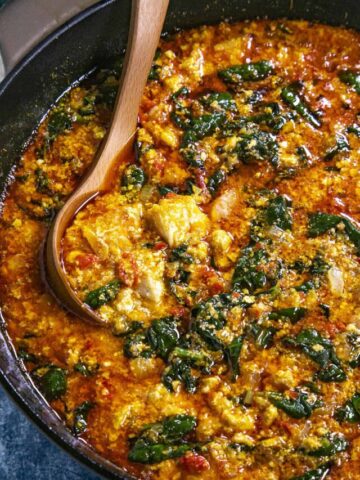 Swirling egusi soup in the pot with a spoon