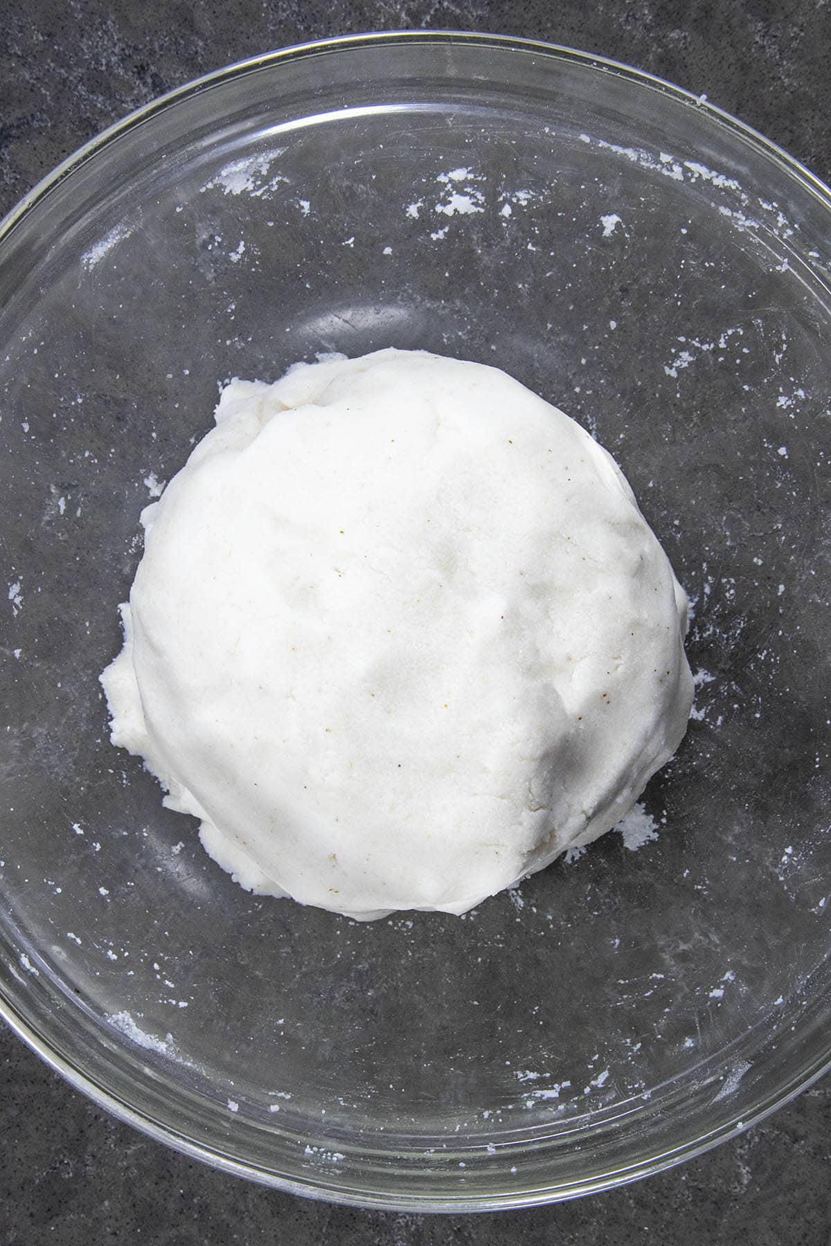 Arepa flour mixed with water and salt to form a dough ball in a bowl