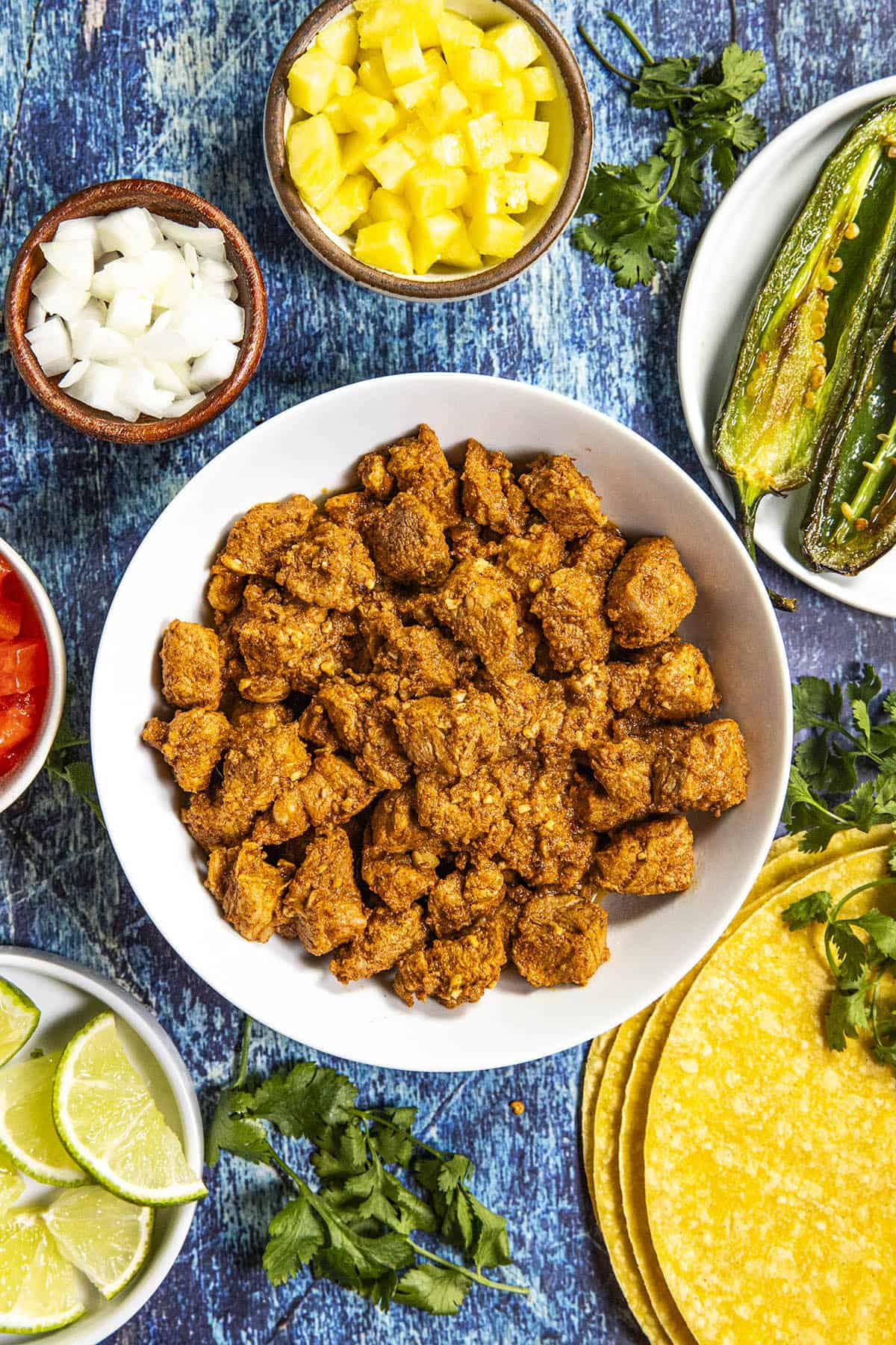 Tacos al pastor in a bowl, served with corn tortillas and lots of topping choices