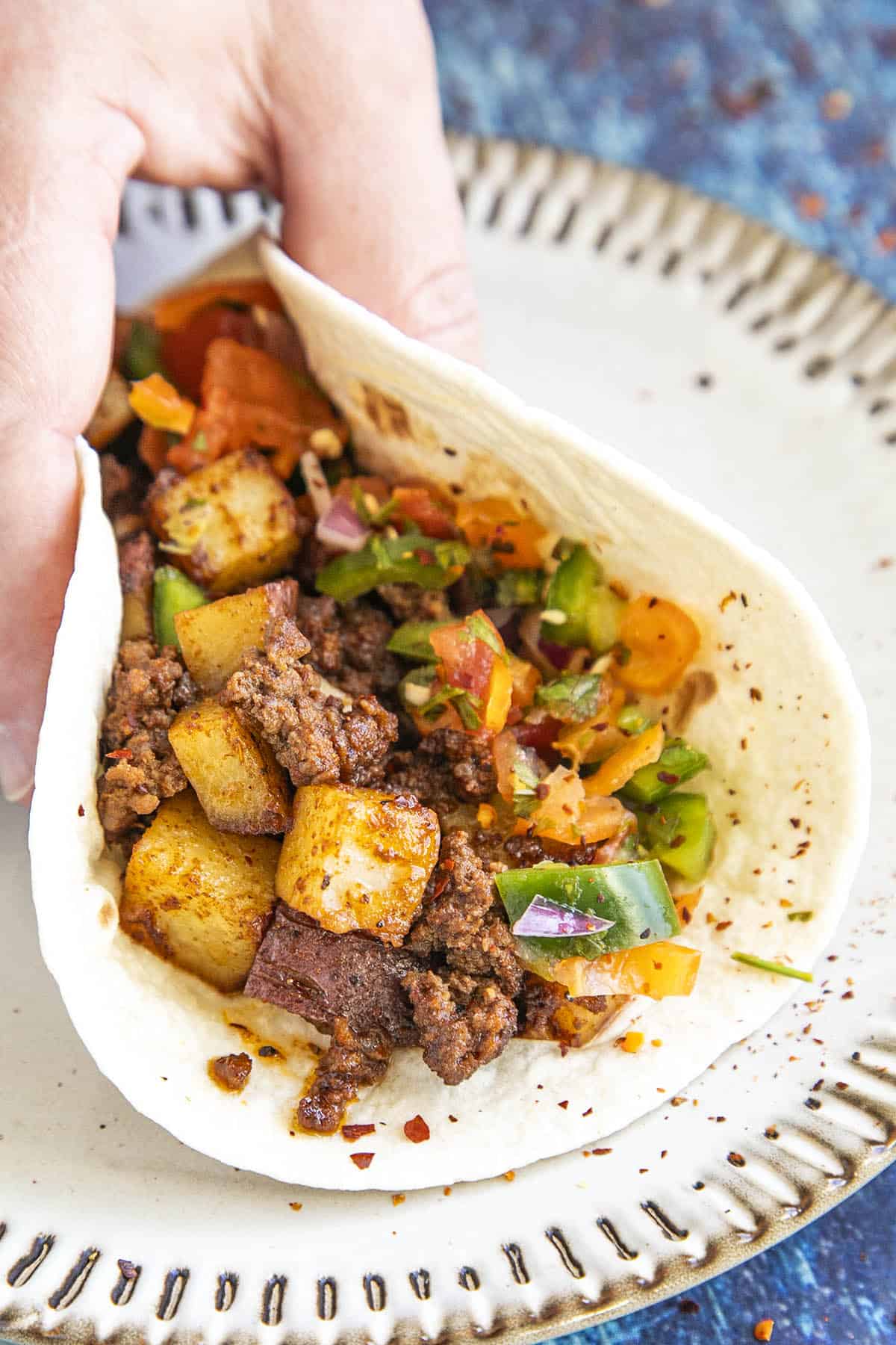 Mike grabbing a Mexican Picadillo taco from a plate