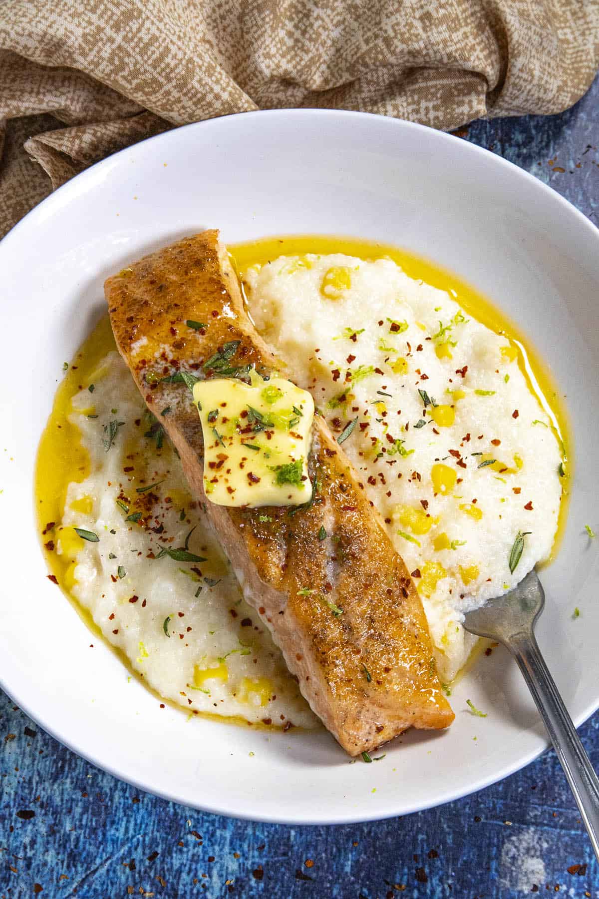Grilled Steelhead Trout on a plate with Chili-Lime Butter, served over cheesy grits