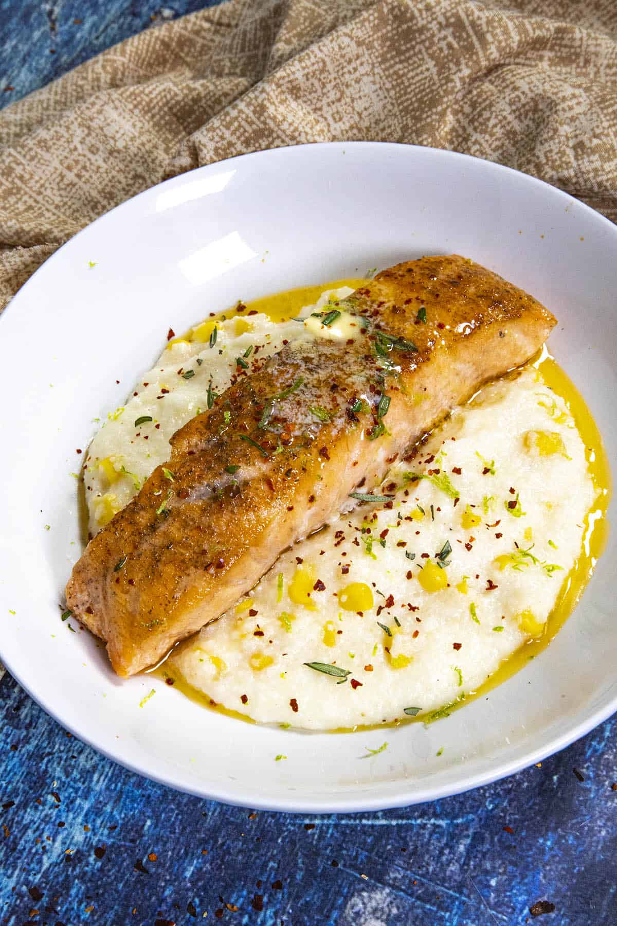 Grilled Steelhead Trout on a plate over creamy grits with Chili-Lime Butter