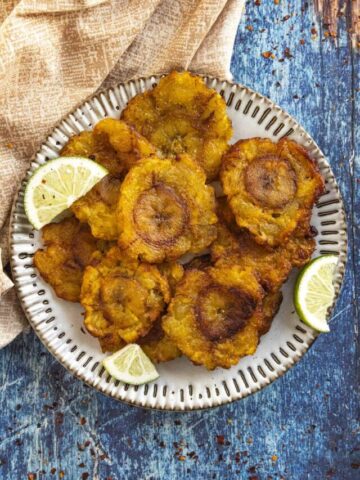 Tostones on a plate with lime wedges, ready to eat