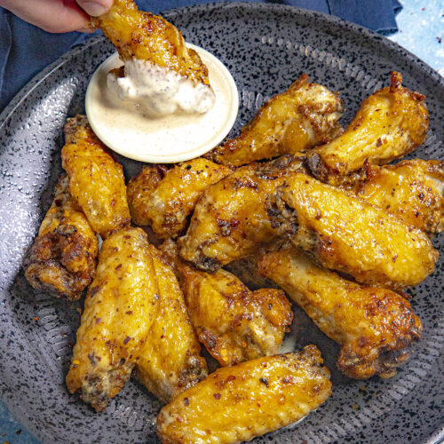 Mike dipping a juicy chicken wing into a bowl of Alabama white bbq sauce