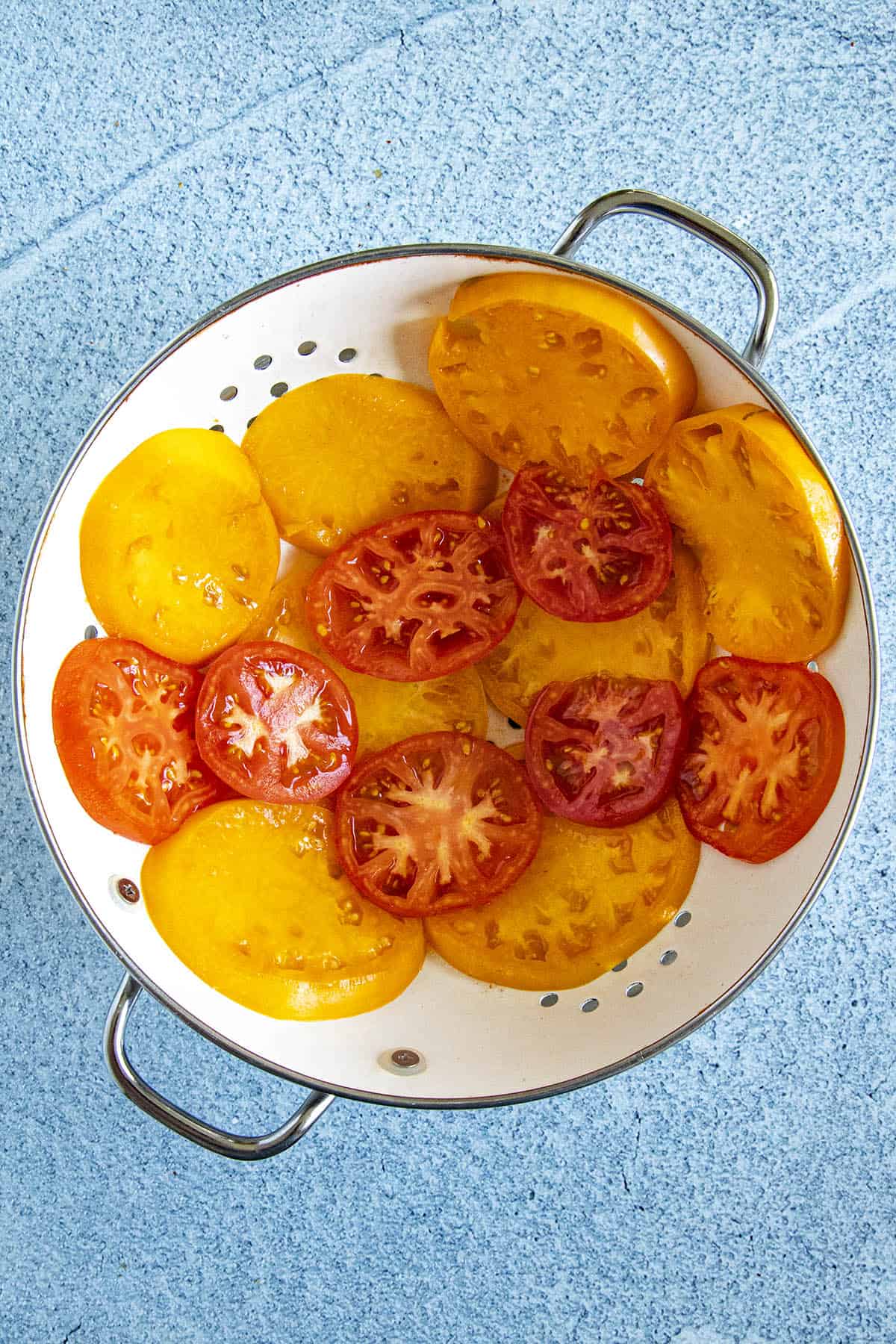 Draining sliced tomatoes in a colander to make Southern Tomato Pie
