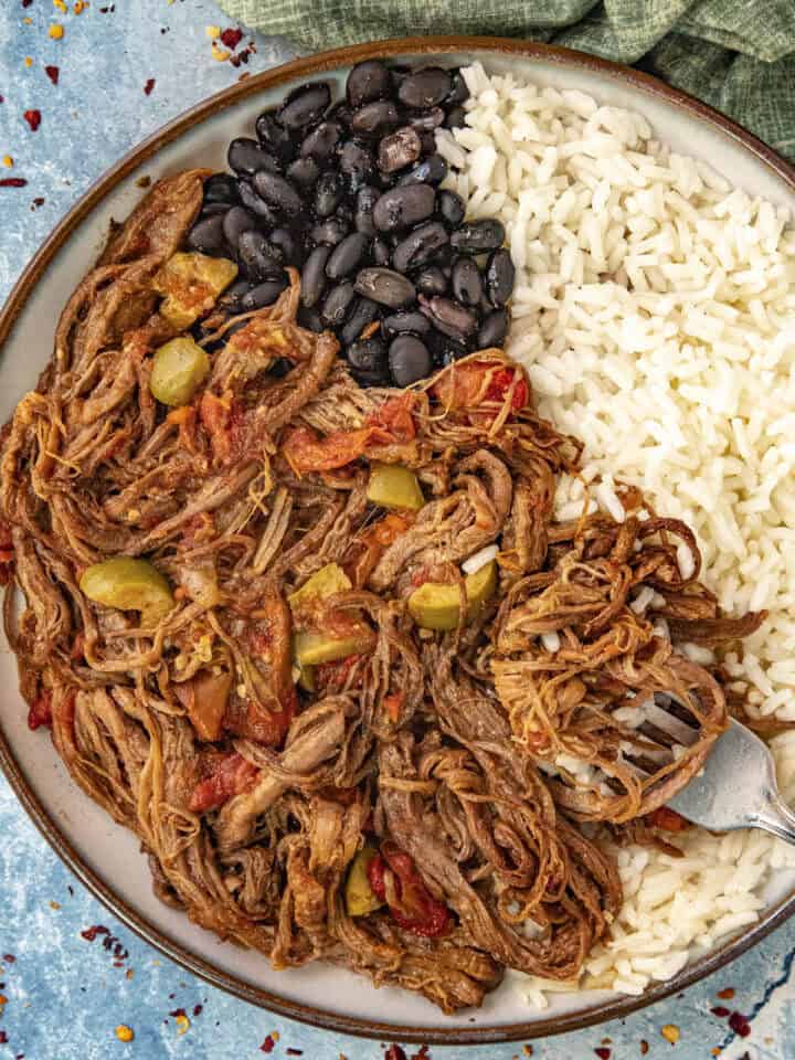 Ropa Vieja (Cuban Shredded Beef) in a bowl with rice and black beans
