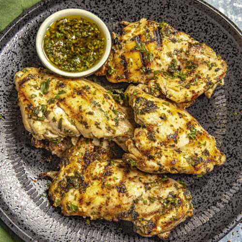 Chimichurri Chicken on a plate with extra chimichurri sauce