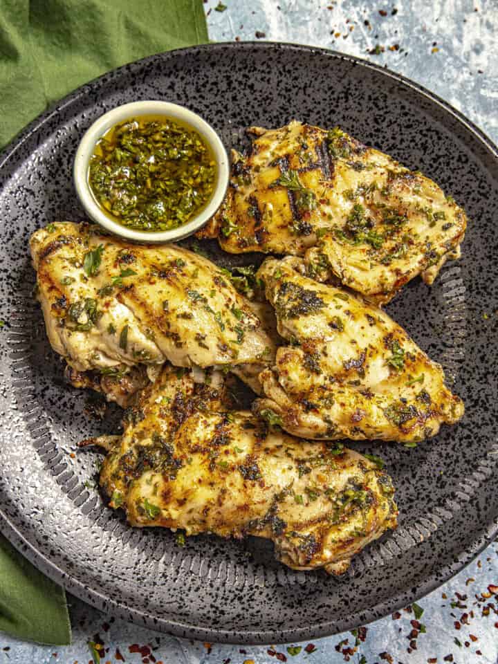 Chimichurri Chicken on a plate with extra chimichurri sauce