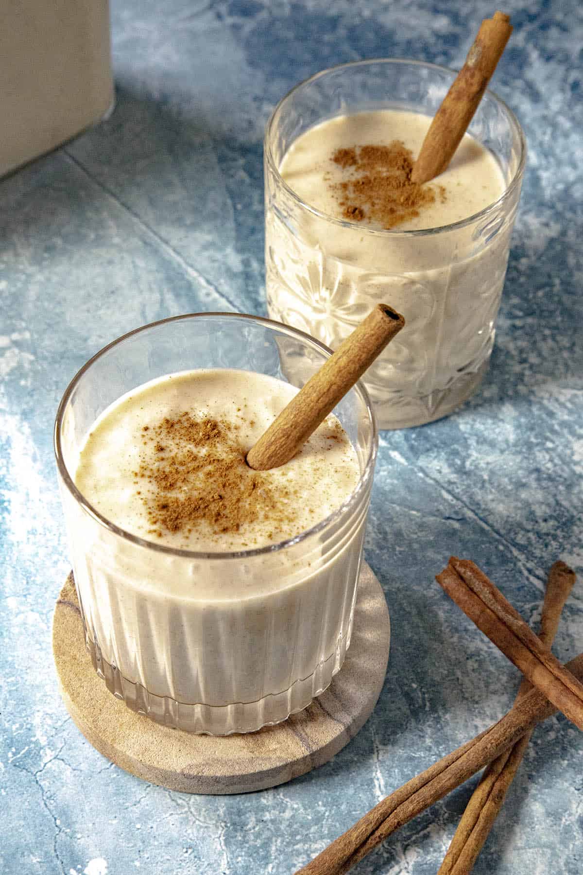 2 glasses of coquito, sprinkled with cinnamon
