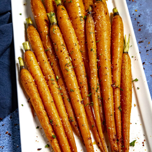 Hot Honey Roasted Carrots on a plate, drizzled with extra hot honey, chili flakes, and flaky sea salt