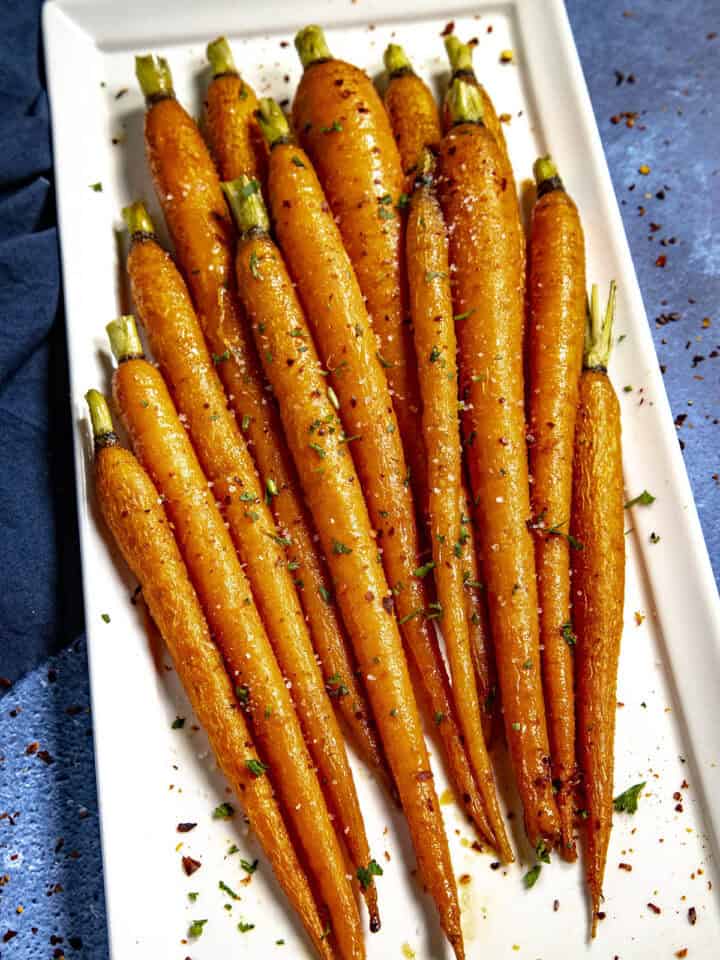 Hot Honey Roasted Carrots on a plate, drizzled with extra hot honey, chili flakes, and flaky sea salt