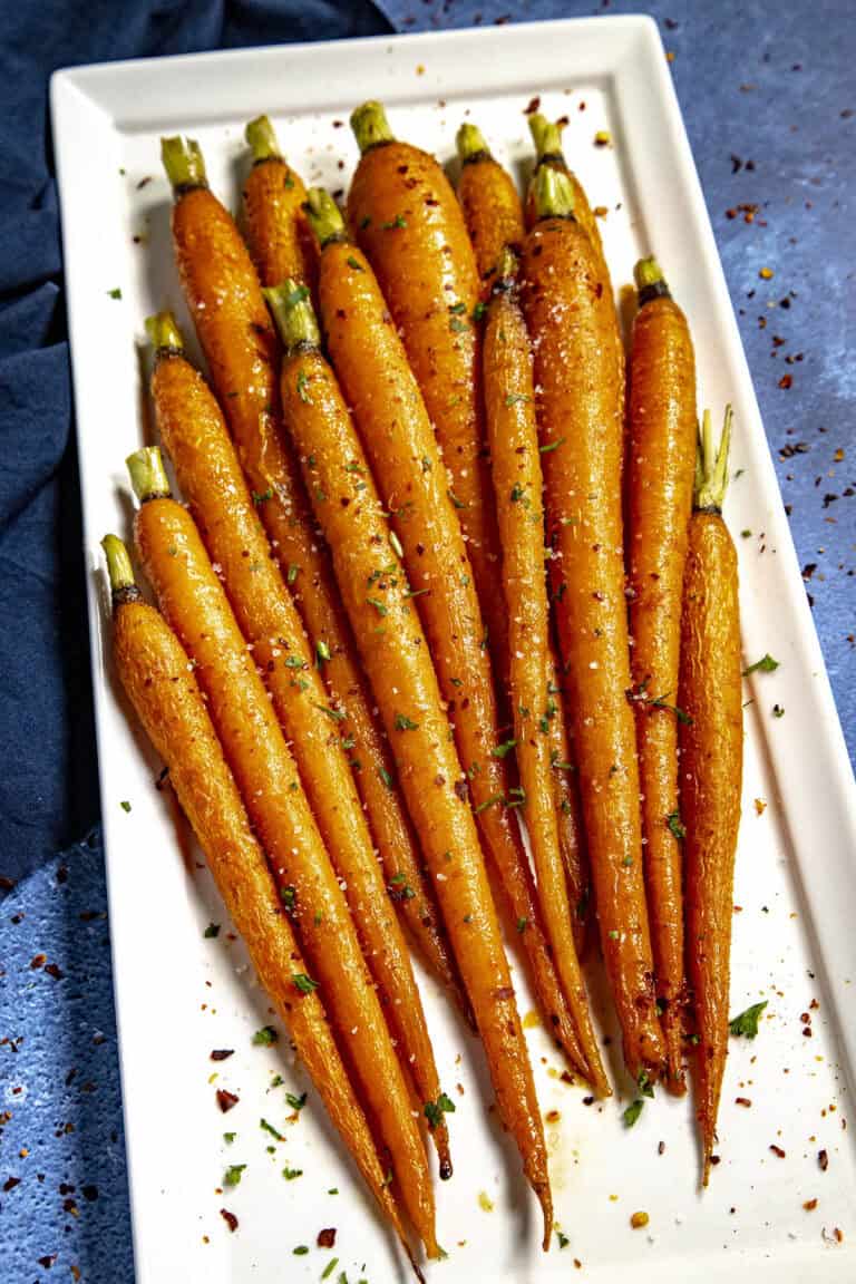 Hot Honey Roasted Carrots on a plate, drizzled with extra hot honey, chili flakes, and flaky sea salt