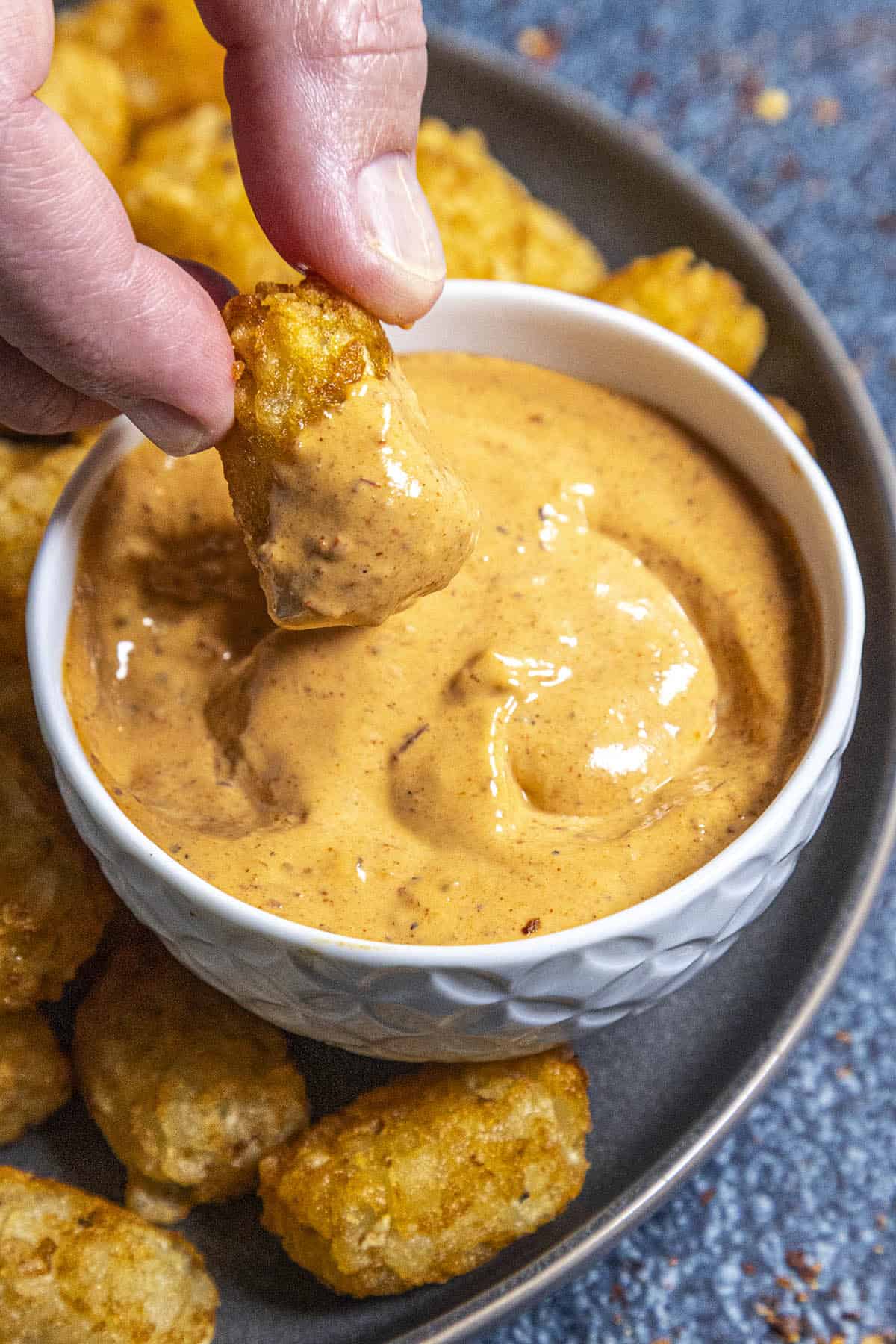 Mike dipping a crispy tater tot into a bowl of creamy chipotle mayo