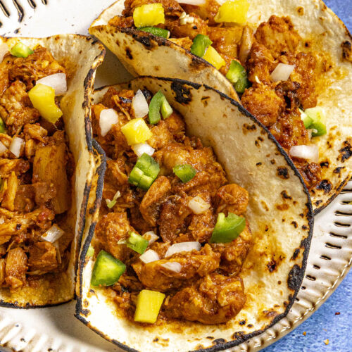 3 Chicken al Pastor tacos on a plate, ready to be enjoyed.