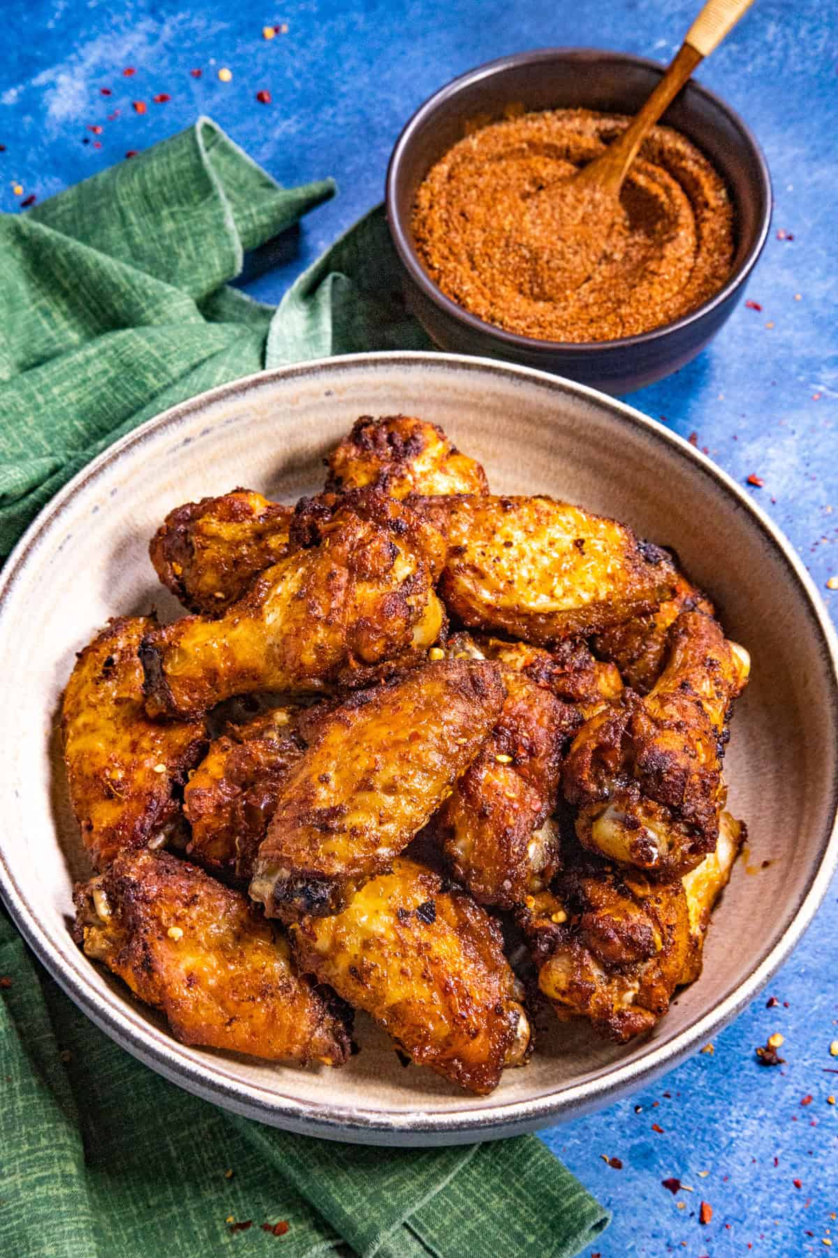 A bowl of crispy chicken wings next to a bowl of my chicken wing dry rub