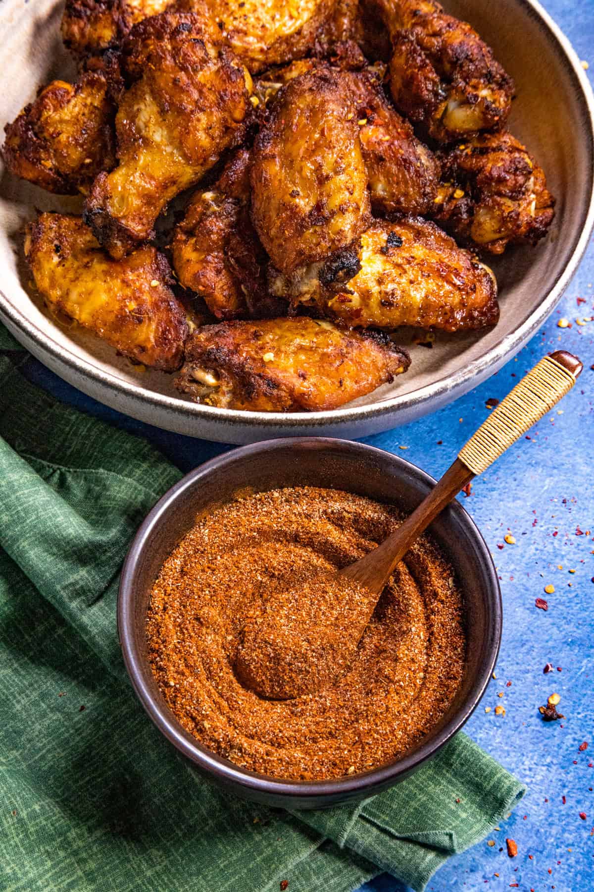 Dry rub for chicken wings in a bowl with cooked chicken wings in another bowl