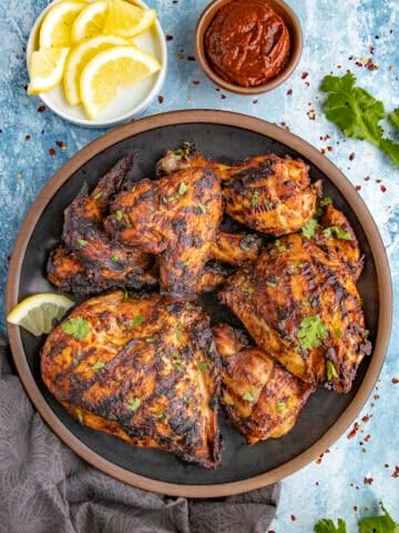 Zesty Grilled Harissa Chicken served with fresh herbs and lemon slices