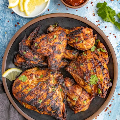 Zesty Grilled Harissa Chicken served with fresh herbs and lemon slices