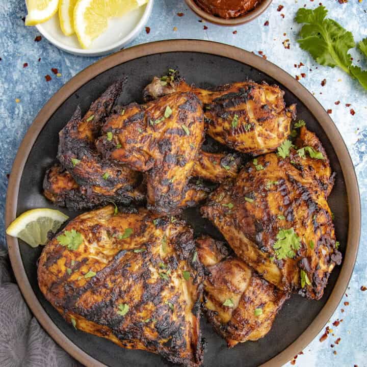 Zesty Grilled Harissa Chicken served with fresh herbs and lemon slices