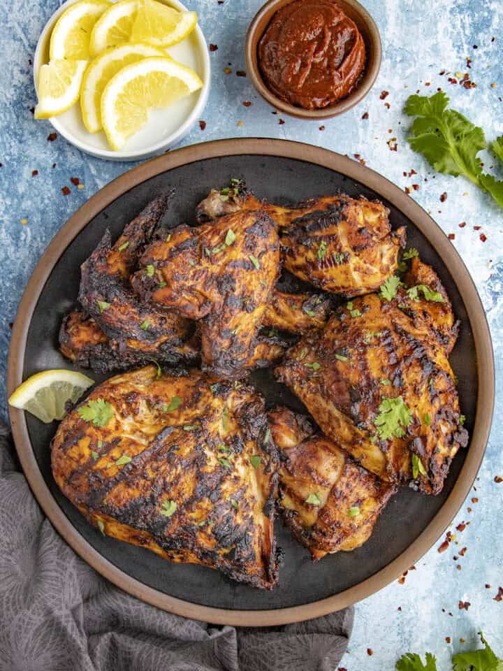 Zesty Grilled Harissa Chicken served with fresh herbs and lemon slices