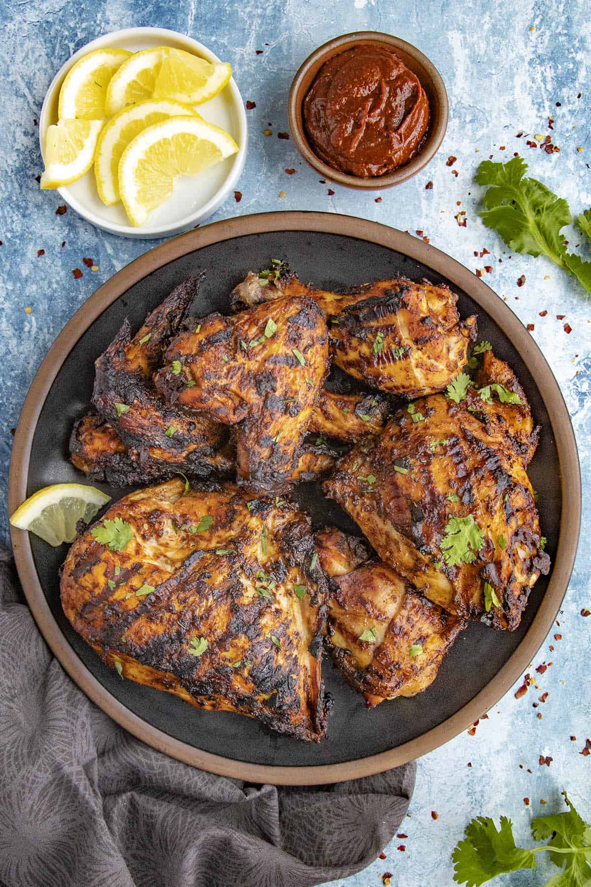 Zesty Grilled Harissa Chicken served with fresh herbs and lemon slices
