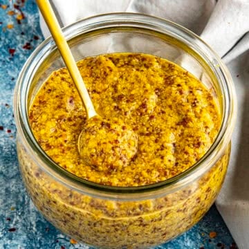A jar of spicy Homemade Honey Beer Mustard with a serving spoon