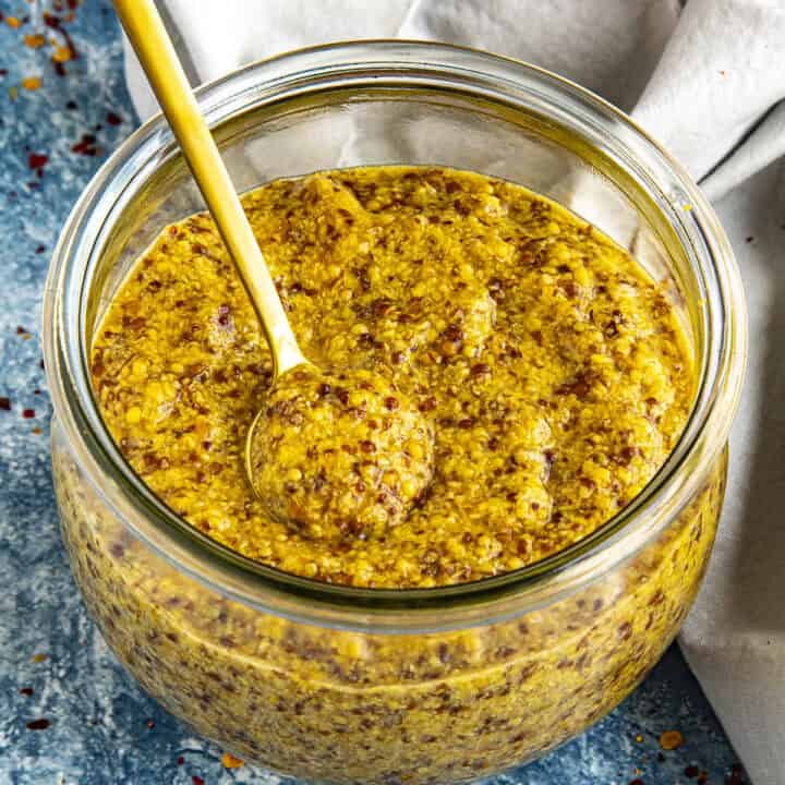A jar of spicy Homemade Honey Beer Mustard with a serving spoon