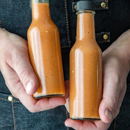 Mike holding two bottles of sweet and spicy Mango-Habanero hot sauce