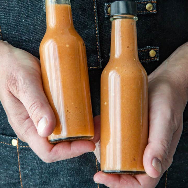 Mike holding two bottles of sweet and spicy Mango-Habanero hot sauce
