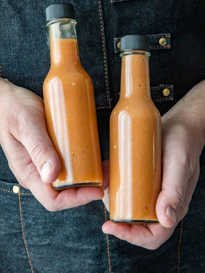 Mike holding two bottles of sweet and spicy Mango-Habanero hot sauce
