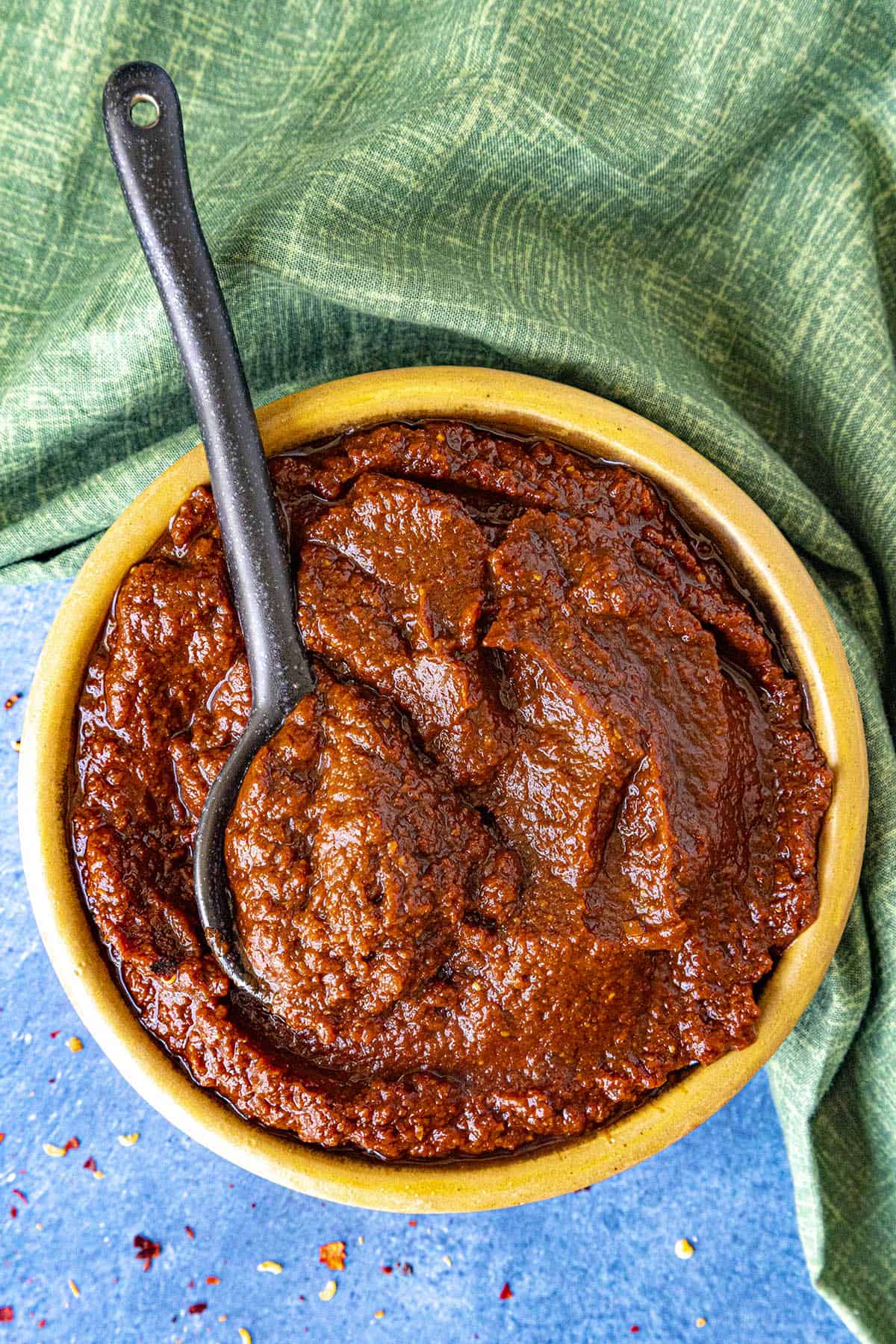A bowl of al Pastor Marinade, which is a thick chili paste, with a serving spoon