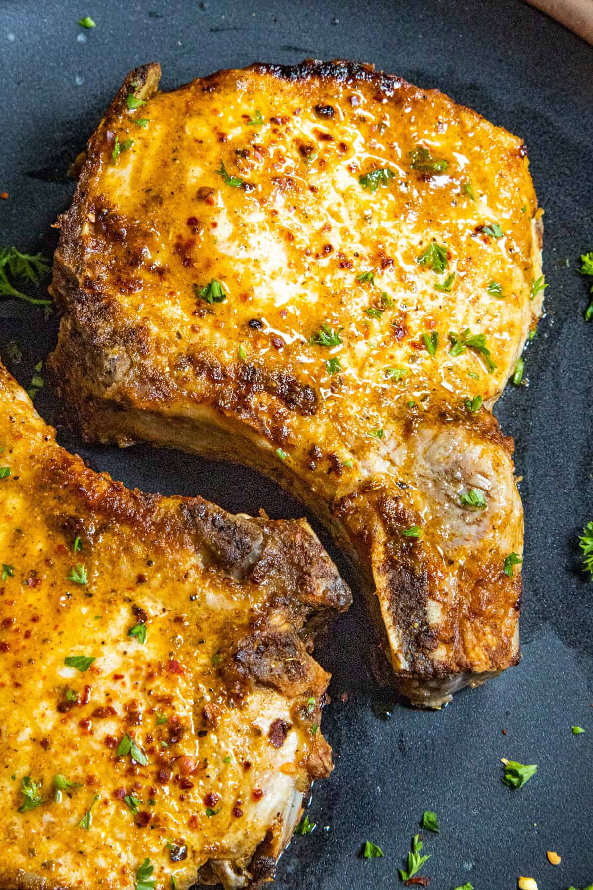 Two perfectly cooked Air Fryer Pork Chops on a plate with garnish