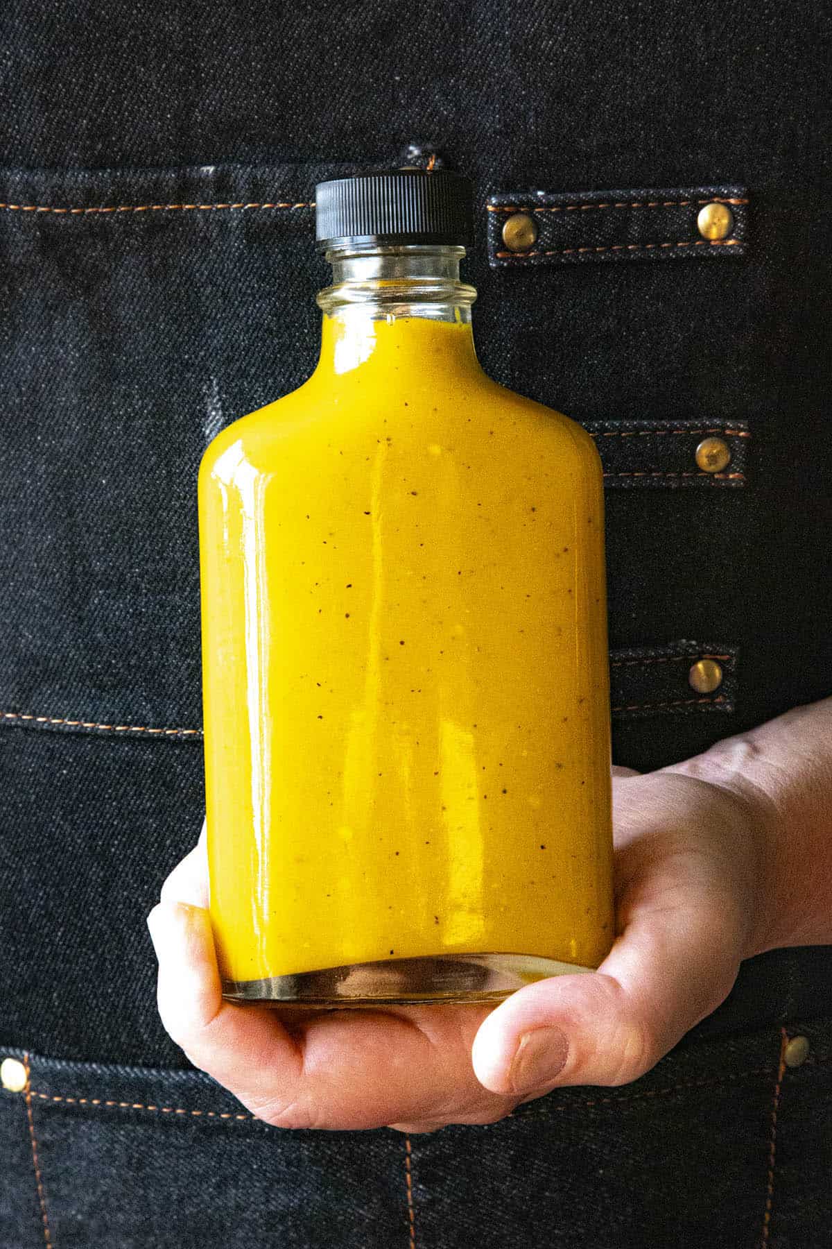 Mike holding a bottle of vibrant yellow Bajan Hot Sauce