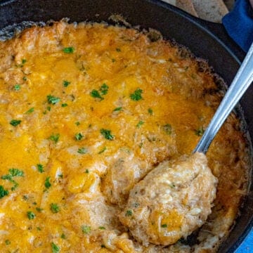 Taking a scoop from the pan of hot crab dip with a spoon to serve