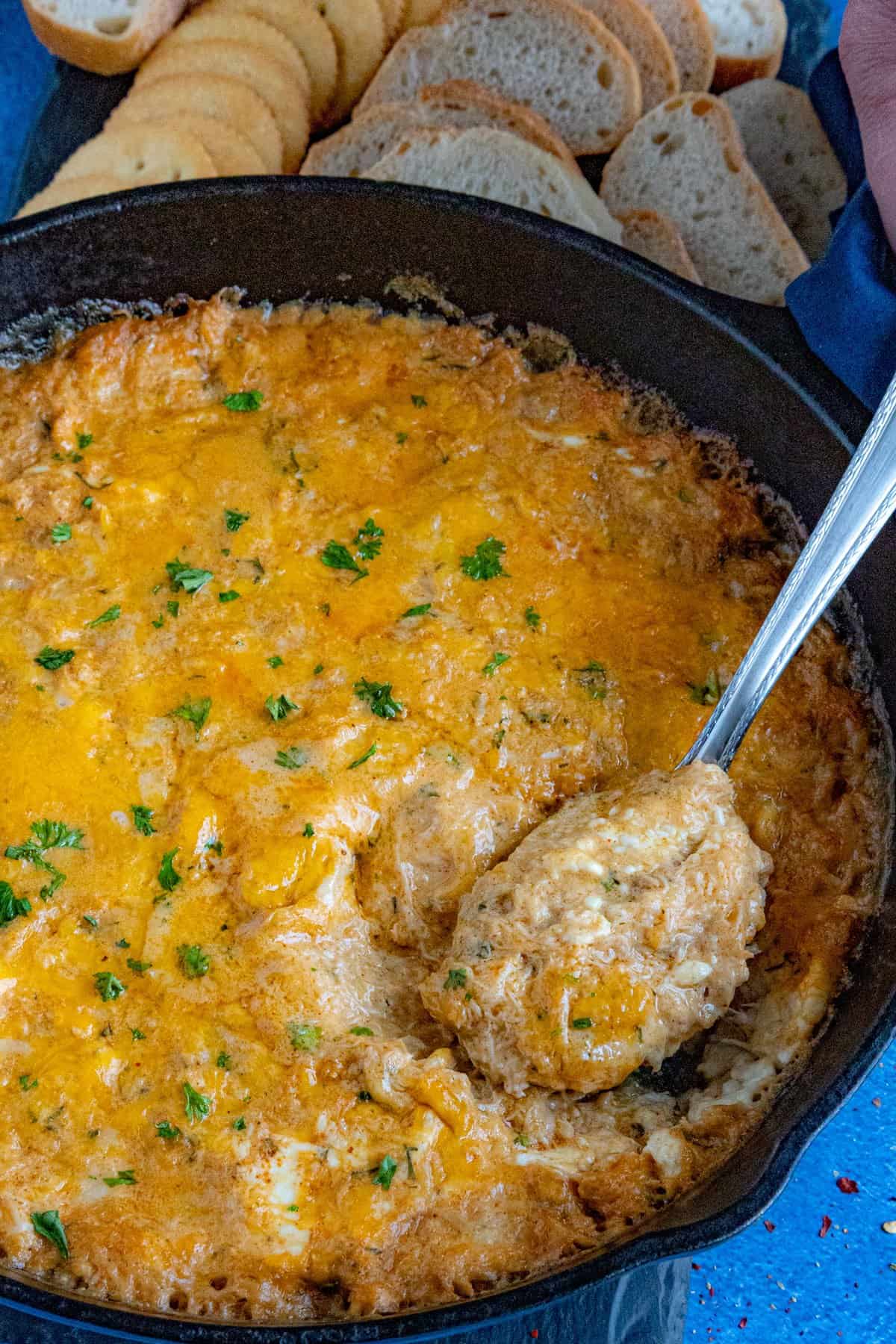 Taking a scoop from the pan of hot crab dip with a spoon to serve