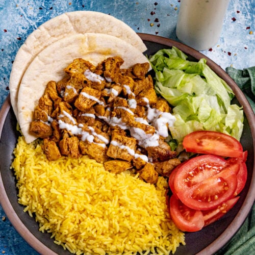 (Halal Cart Style Chicken on a serving plate with yellow rice, simple salad, drizzled with Halal white sauce