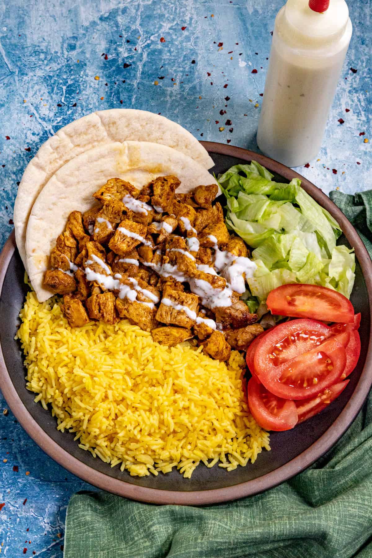 (Halal Cart Style Chicken on a serving plate with yellow rice, simple salad, drizzled with Halal white sauce