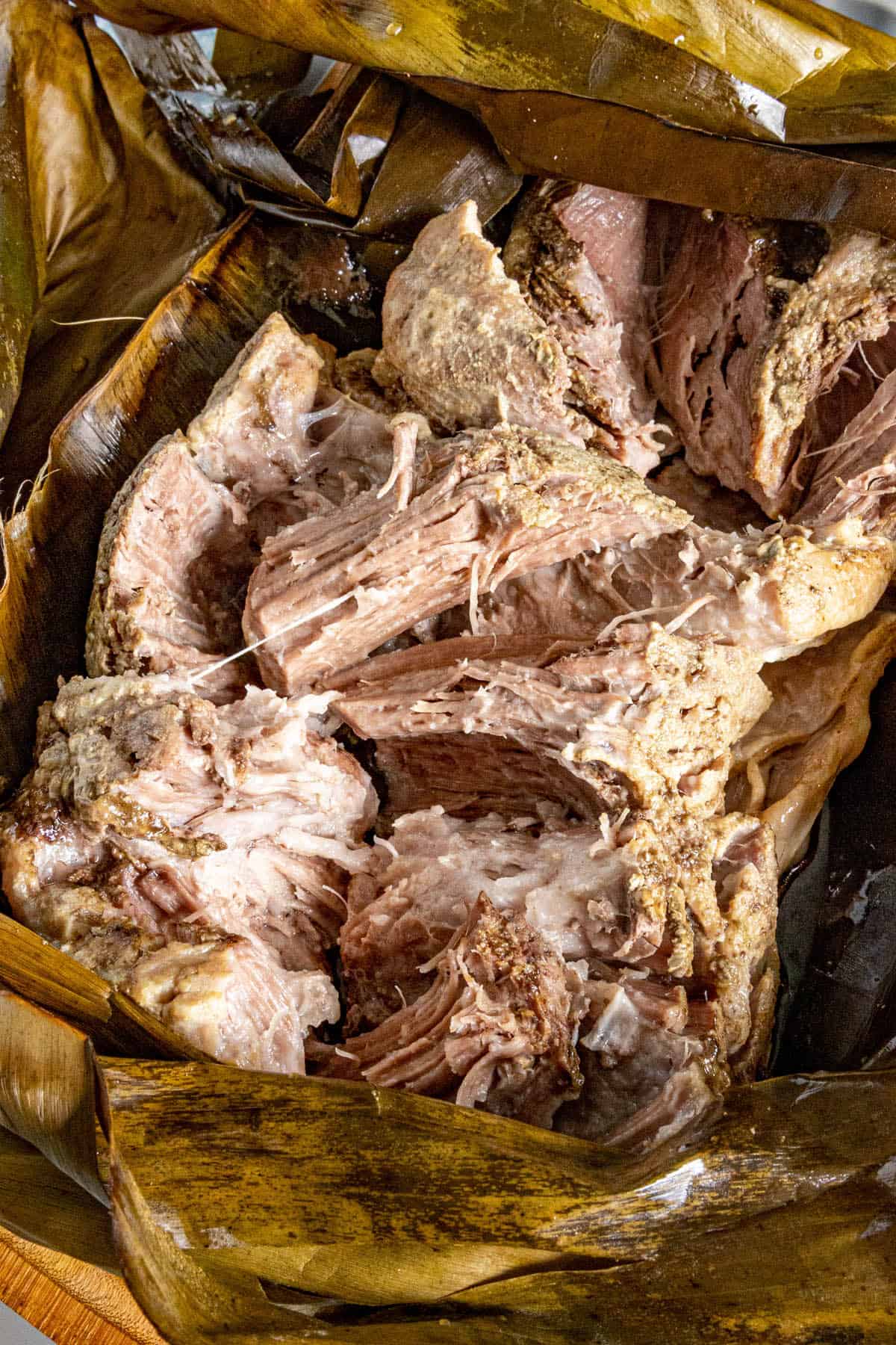 Kalua wrapped in a banana leaf, being shredded
