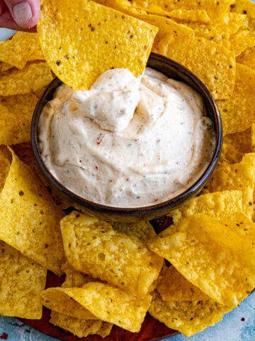 Dipping a crispy tortilla chip into a bowl of Mexican White Sauce (Salsa Blanca)