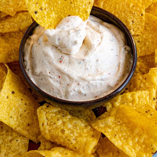 Dipping a crispy tortilla chip into a bowl of Mexican White Sauce (Salsa Blanca)